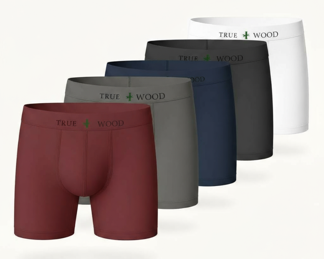 Five men's boxer briefs displayed in a row, featuring maroon, gray, navy blue, black, and white colors. Each waistband reads 'TRUE WOOD' with a green leaf icon in the center, using a clean serif font and consistent style for all pairs.